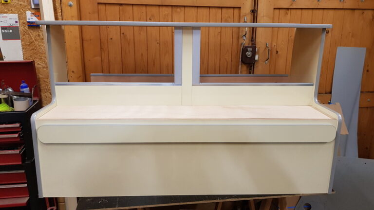 Un ensemble de pièces de bois revêtu de stratifié couleur ivoire formant ainsi plusieurs coffres de rangement pour l'aménagement d'un renault trafic L2H1.